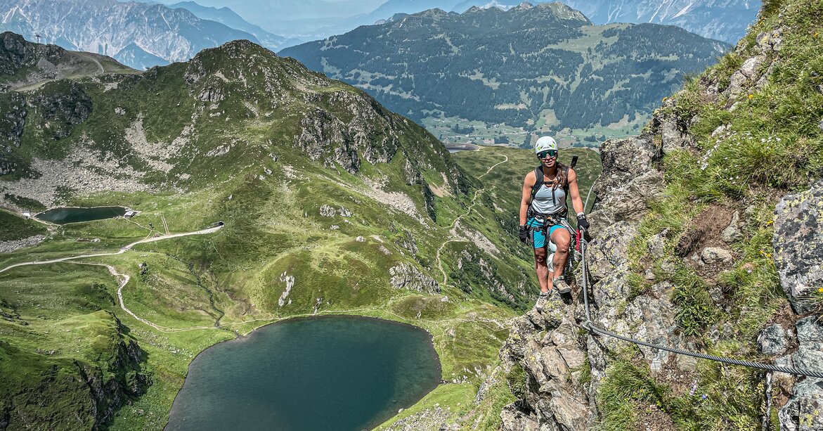 Kletterin am Klettersteig Hochjoch - Silvretta Montafon | © Silvretta Montafon - Vanessa Strauch Eine Kletterin steht am Seil im Klettersteig mit Blick ins Seetal am Hochjoch in der Silvretta Montafon. | © Silvretta Montafon - Vanessa Strauch