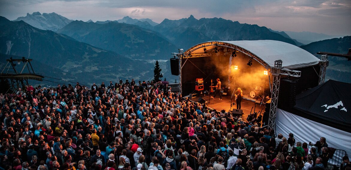 Ein Konzert beim Sonnenuntergang mit bunter Beleuchtung und großem Publikum | © Silvretta Montafon - Frederike Weber