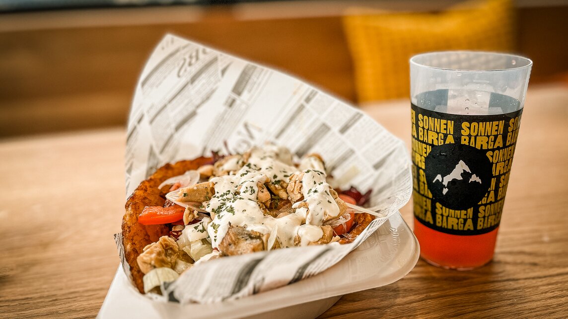 Alpendöner - Silvretta Montafon | © Silvretta Montafon - Vanessa Strauch Ein Alpendöner mit Getränk in der Sonnen Barga in der Silvretta Montafon. | © Silvretta Montafon - Vanessa Strauch