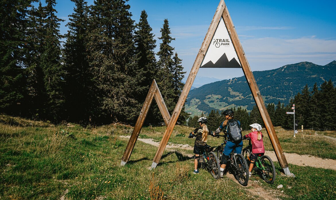 Eine Familie mit einer Frau und zwei Kindern am Eintrittsportal zum Trailpark am Hochjoch in der Silvretta Montafon.  | © Silvretta Montafon - Vanessa Strauch