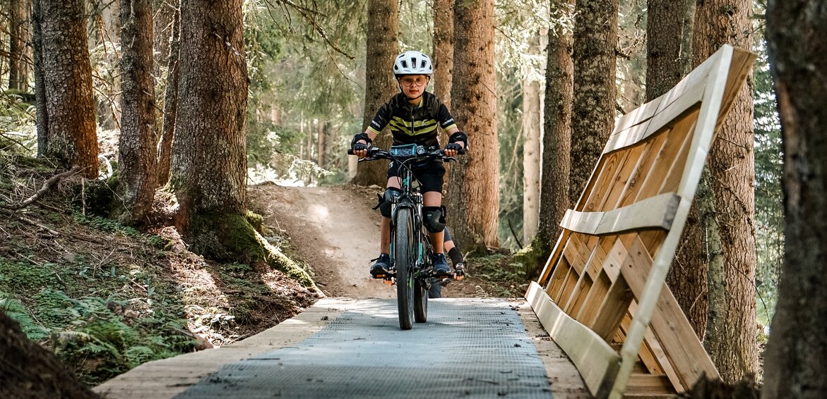 Eine Mädchen fährt auf einem Biketrail im Wald am Hochjoch in der Silvretta Montafon. | © Silvretta Montafon - Vanessa Strauch