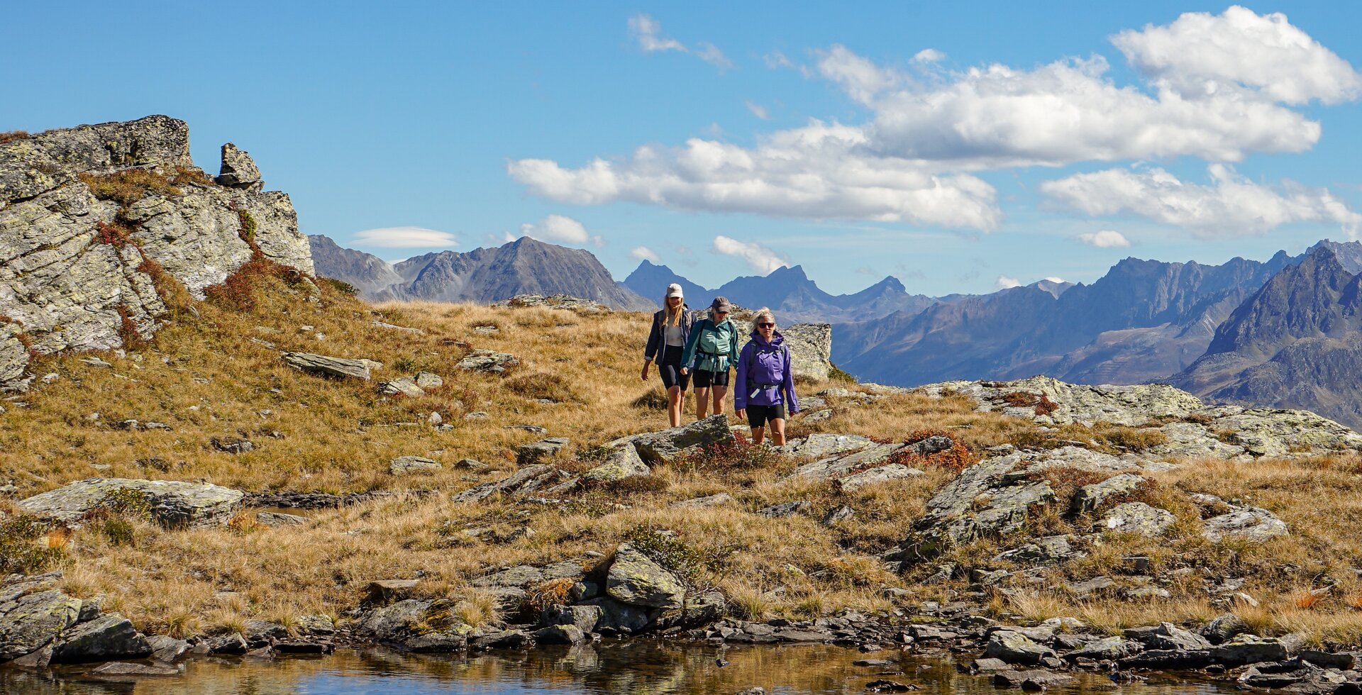 Madrisella Gipfelweg - Silvretta Montafon | © Silvretta Montafon - Vanessa Strauch Drei junge Frauen wandern im herbstlichem Gebirge zu einem Bergsee. | © Silvretta Montafon - Vanessa Strauch