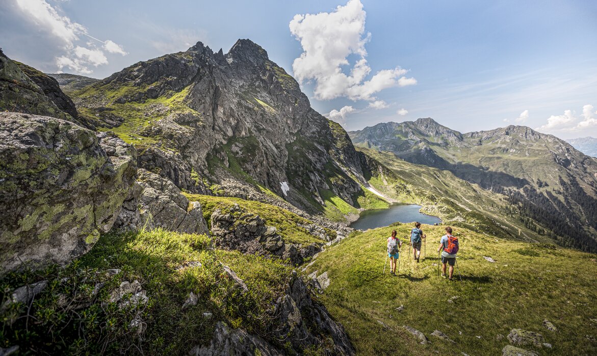 Drei Personen wandern Richtung Herzsee im Sommer am Hochjoch in der Silvretta Montafon. | © Silvretta Montafon - Stefan Kothner