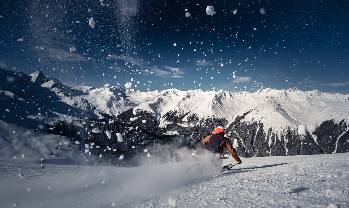 Ein Skifahrer auf der Piste und spritzender Schnee im Vordergrund. | © Silvretta Montafon - Daniel Hug