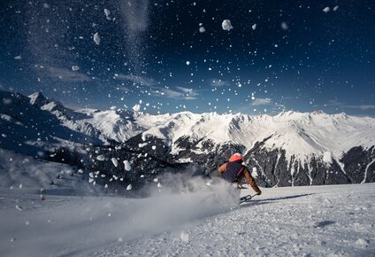 Ein Skifahrer auf der Piste und spritzender Schnee im Vordergrund. | © Silvretta Montafon - Daniel Hug