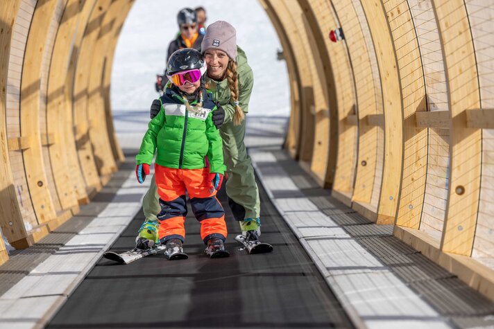 Förderband Valisera - Silvretta Montafon | © Silvretta Montafon - Torsten Wenzler Eine Mutter steht mit ihrer Tochter auf dem überdachten Förderband an der Valisera Bahn Bergstation in der Silvretta Montafon. | © Silvretta Montafon - Torsten Wenzler