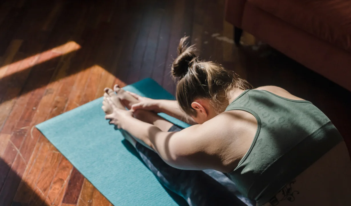 Eine Frau macht eine Yoga-Übung auf einer Matte | © Tina Fehrenbach - Silvretta Montafon